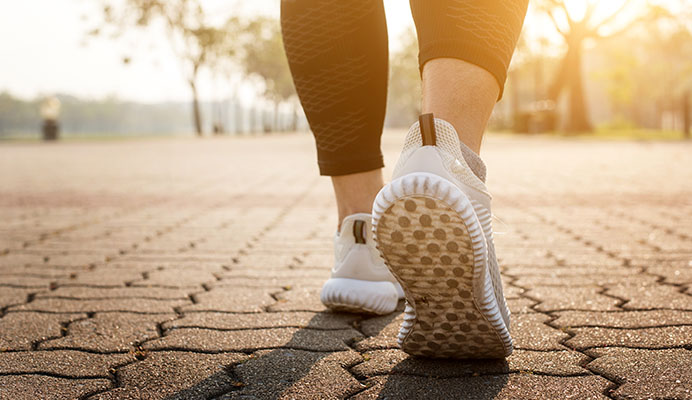 view of sneakers of woman walking to maintain wellness